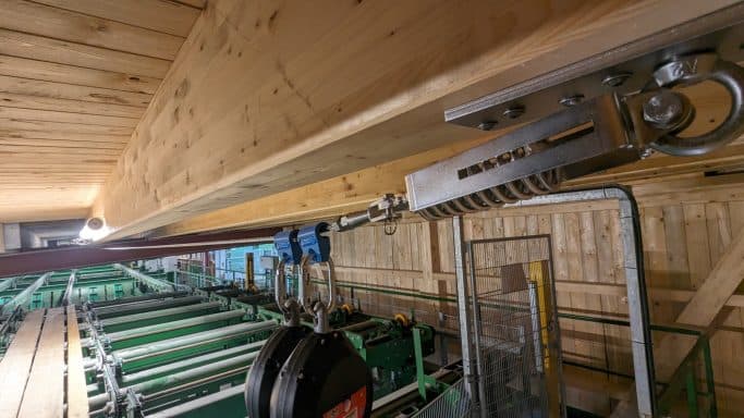 Gleisanlage mit einem Hebemechanismus an einem Holzträger in einer Lagerhalle.