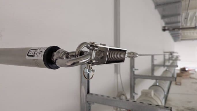 Detailansicht eines Metallbeschlags an einem Rohr in einem Bauumfeld.
